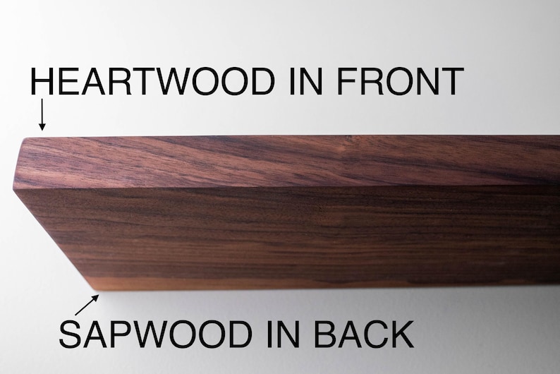 May include: Close-up of a section of hardwood, showcasing the grain and color variations. The text indicates "HEARTWOOD IN FRONT" and "SAPWOOD IN BACK", highlighting the wood's natural features. The wood has a rich, dark brown hue.