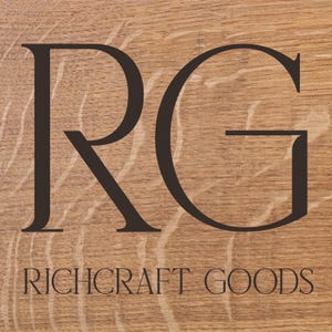 May include: A wooden sign with the letters "RG" in black, followed by the text "RICHCRAFT GOODS" in black.