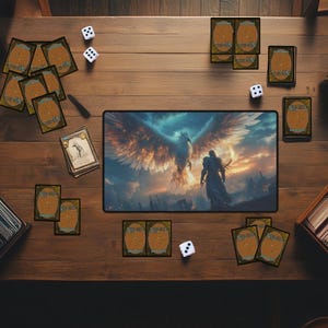 May include: A tabletop game scene with a variety of playing cards, dice, and a game mat featuring a fantasy illustration of a winged creature and a person in armor.