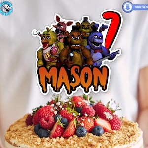May include: A cake topper featuring characters from the Five Nights at Freddy's video game series. The topper includes Freddy Fazbear, Bonnie the Bunny, Chica the Chicken, Foxy the Pirate Fox, and a red number 7. The topper also includes the name "MASON" in orange dripping letters.