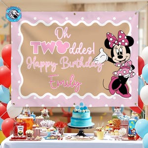 May include: A rectangular pink and tan birthday banner featuring a scalloped white border with polka dots. The text reads Oh TWOddes! Happy Birthday Emily. A graphic of Minnie Mouse wearing a pink polka dot dress and bow is on the right side.