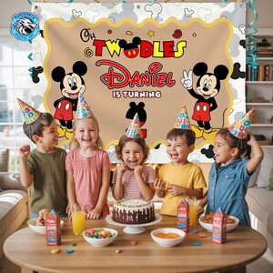 May include: A rectangular party backdrop featuring a tan center with a scalloped yellow border, decorated with two Mickey Mouse illustrations, the text "Oh Twodles", "Daniel is turning", and a large number "2" in black silhouette.