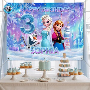 May include: A birthday party banner featuring Elsa and Anna from Frozen, with the text "Happy Birthday" and "Sophia". The number "3" is prominently displayed. The scene includes a cake, cupcakes, and macarons, creating a festive atmosphere.