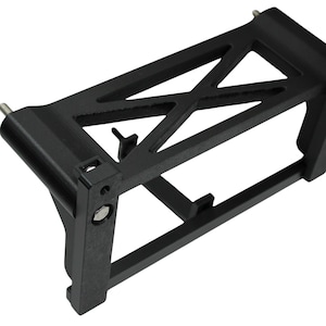 May include: A black, rectangular bracket with an open, geometric design. The bracket features intersecting bars and supports, with metal pins and fasteners. The object is made of a matte black material.
