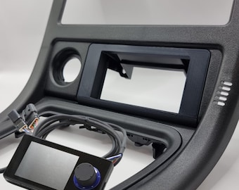 May include: A black car dashboard kit with a blank screen and a black control panel with a blue knob. The kit includes a wiring harness.
