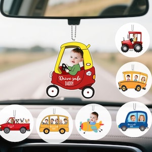 May include: A collection of car air fresheners featuring personalized photos. The main freshener is a red and yellow car with a baby photo and the text "Drive safe DADDY." Other designs include a tractor, school bus, car, and airplane, each with a photo.