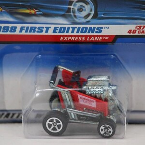 May include: A red and silver toy car from the 1998 First Editions series, labeled "Express Lane." The car is in a clear plastic package, with the text "#37 of 40 Cars" visible on the packaging.