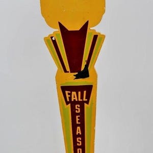 Peut inclure: Un ancien tire-bouchon de bière jaune et marron avec les mots "Wilhelm Scream" en haut. La poignée a un design stylisé avec les mots "Fall Seasonal" en texte vertical.
