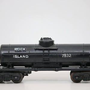 Op de afbeelding: Zwarte modeltreinwagon met de woorden "ROCK ISLAND" en het nummer "7832" in het wit. De wagon heeft een cilindrische tank en staat op een zwart chassis met wielen. Het model staat tegen een witte achtergrond.