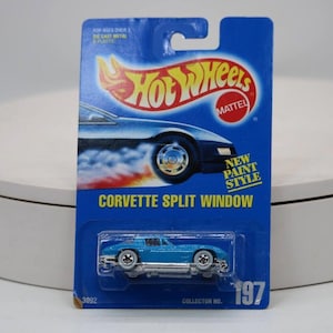 May include: A blue Hot Wheels die-cast toy car of a Corvette Split Window model, packaged on a blue card. The card features the Hot Wheels logo, a graphic of the car, and the text "NEW PAINT STYLE". Collector No. 197.