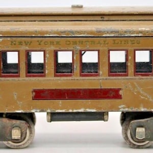 Può includere: Un vagone di un treno giocattolo vintage dipinto di marrone con accenti rossi. Il vagone ha un cartello con la scritta "New York Central Lines".