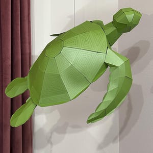 May include: A geometric, green paper turtle sculpture with a detailed shell pattern. The turtle is suspended in the air, showcasing its three-dimensional form and angular design. The sculpture is a vibrant shade of green.