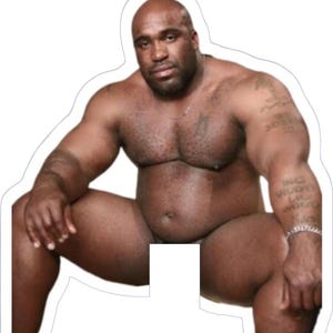 May include: A die-cut sticker featuring a muscular, bald, dark-skinned person with a beard, sitting with legs spread. The person is shirtless, with tattoos on the right arm and a silver chain necklace. The background is white.