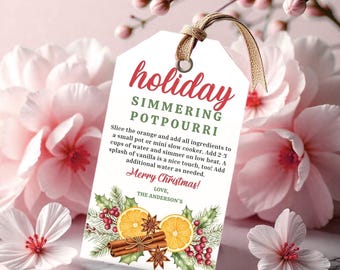 May include: A white tag with the words "holiday simmering potpourri" in red script. The tag includes instructions and a decorative image of orange slices, cinnamon sticks, and star anise. The tag is tied with a natural twine and ribbon.