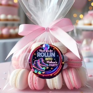 May include: A cellophane bag tied with a pink ribbon, filled with pink and white macarons. A circular tag reads "Thank You for Rollin' into Melissa's Party" with roller skates and neon lights.