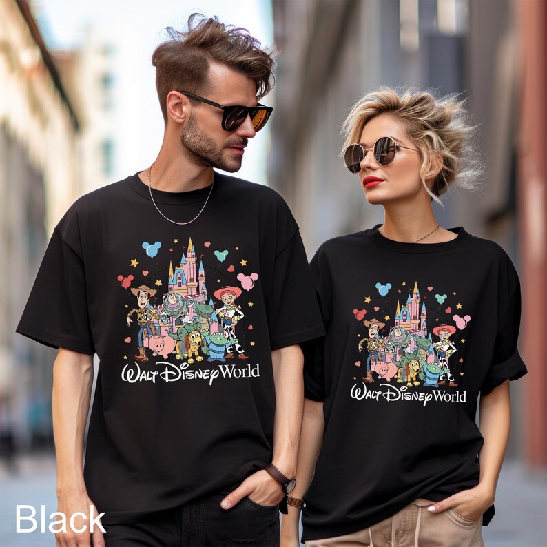 May include: Black t-shirts featuring a colorful graphic of Disney characters and a castle, with the text "Walt Disney World". The shirts are worn by two people. The word "Black" is printed at the bottom left.