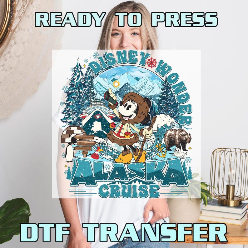 May include: White t-shirt featuring a colorful graphic of Minnie Mouse in winter attire, with the text "Disney Wonder Alaska Cruise". The design includes a bear, mountains, and an igloo. The words "Ready to Press" and "DTF Transfer" are also visible.