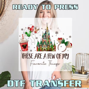 May include: White t-shirt featuring a colorful graphic with a castle, balloons, a drink, and a headband. The text "THESE ARE A FEW OF MY Favorite Things" is displayed. The words "READY TO PRESS" and "DTF TRANSFER" are also visible.