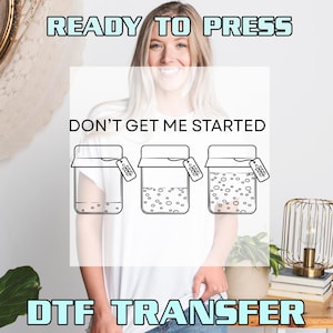May include: White t-shirt with the text "DON'T GET ME STARTED" and three jars with varying levels of bubbles. The words "READY TO PRESS" and "DTF TRANSFER" are also in the image. The design is a DTF transfer.