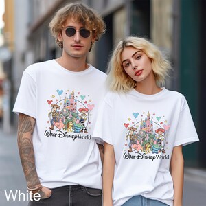 May include: White t-shirts featuring a colorful graphic of Disney characters and a castle, with the text "Walt Disney World". The shirts are worn by two people.