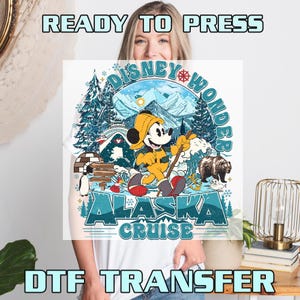 May include: A white t-shirt featuring a colorful graphic of Mickey Mouse in Alaska. The design includes text that reads "Disney Wonder Alaska Cruise". The image also includes text that reads "READY TO PRESS" and "DTF TRANSFER".