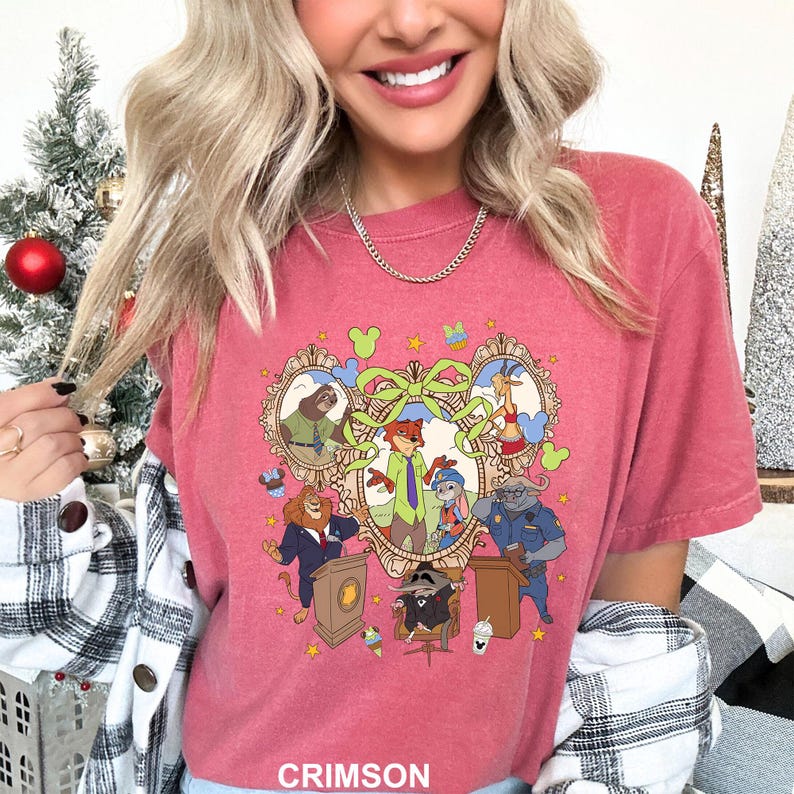 May include: Crimson-colored t-shirt featuring a cartoon illustration of various animal characters in a decorative frame. The design includes characters like a fox, a bunny, and a lion. The word "CRIMSON" is printed at the bottom.