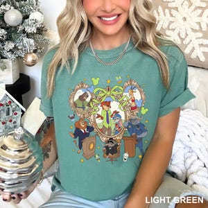 May include: Light green t-shirt featuring a colorful cartoon graphic of various animal characters in ornate frames. The design includes the text "LIGHT GREEN" at the bottom. The shirt has short sleeves and a relaxed fit.
