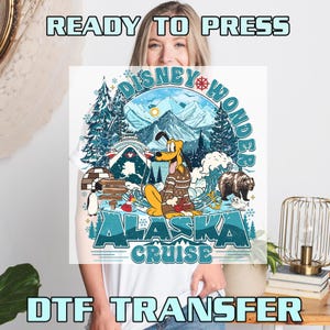 May include: White t-shirt featuring a colorful graphic of Pluto in a sweater, a bear, and an igloo, with the text "Disney Wonder Alaska Cruise." The words "READY TO PRESS" and "DTF TRANSFER" are also visible.