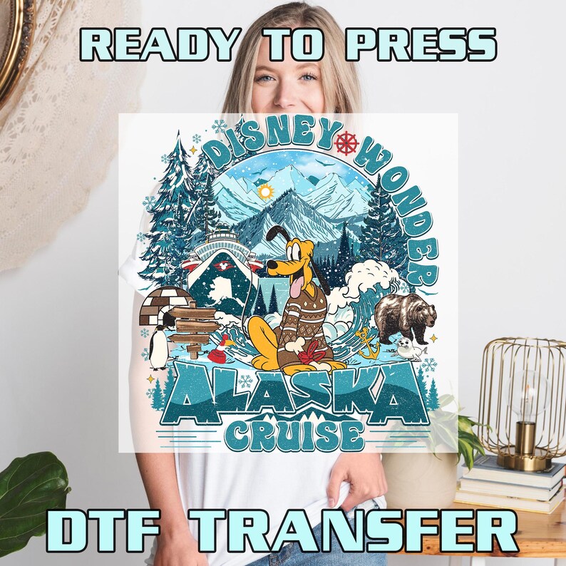 May include: White t-shirt featuring a colorful graphic of Pluto in a sweater, a bear, and an igloo, with the text "Disney Wonder Alaska Cruise." The words "READY TO PRESS" and "DTF TRANSFER" are also visible.