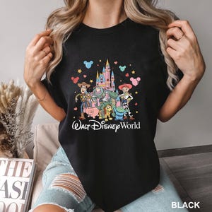 May include: Black t-shirt featuring a colorful graphic of Toy Story characters in front of a castle, with the text "Walt Disney World" in a script font. The design includes Woody, Buzz Lightyear, and other characters.