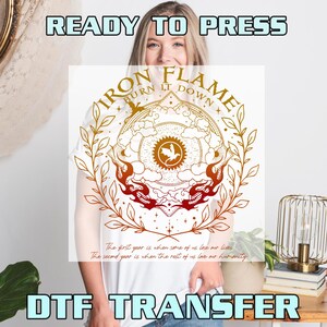 May include: A white DTF transfer sheet featuring a gold and orange graphic with the text "IRON FLAME BURN IT DOWN" and "The first year is when some of us lose our lives. The second year is when the rest of us love our humanity." The design includes a dragon, sun, and leaves.