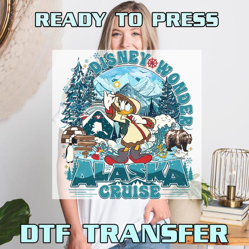 May include: White t-shirt featuring a colorful graphic of Donald Duck in winter attire, with the text "Disney Wonder Alaska Cruise." The design includes snowy mountains, a bear, and an igloo. The words "Ready to Press" and "DTF Transfer" are also visible.