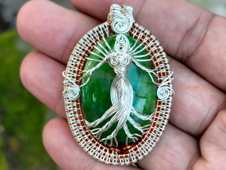 May include: A silver and copper wire wrapped pendant featuring a green agate stone with a silver wire tree of life design.