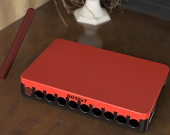 May include: A red rectangular box with the text "RG50x7" and a series of circular openings along one side. A brown, cylindrical object rests nearby. The box is on a brown surface.