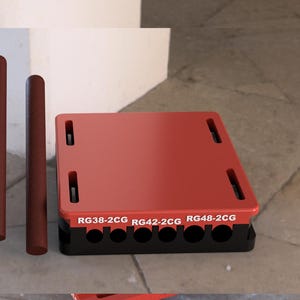 Pode incluir: Plataforma de plástico vermelha e preta com o texto "RG38-2CG RG42-2CG RG48-2CG" impresso na frente. A plataforma tem uma série de furos na parte inferior.