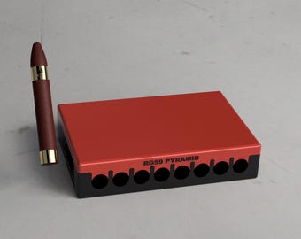 May include: A red box with black trim and the text "RG59 PYRAMID" on the front. The box has eight circular openings and is designed to hold cigars.