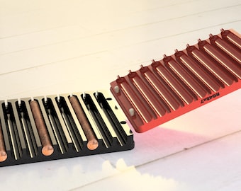 May include: Two black and red cigar holders with a capacity of 10 cigars each. The holders are made of plastic and have a sleek, modern design. The red holder has the word "ROASTY" printed on it.