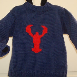 May include: A blue knitted sweater with a red lobster design on the front.