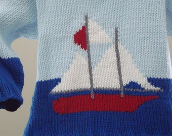 Könnte beinhalten: Ein blauer und weißer Strickpullover mit einem roten und weißen Segelboot-Design. Der Pullover hat ein blaues und weißes Farbblockmuster.