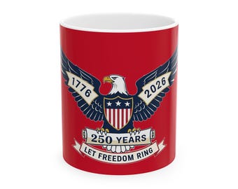 May include: A red ceramic mug featuring a patriotic design. The design includes a bald eagle with outstretched wings, the years 1776 and 2026, and the text "250 YEARS" and "LET FREEDOM RING". The mug has a white interior.