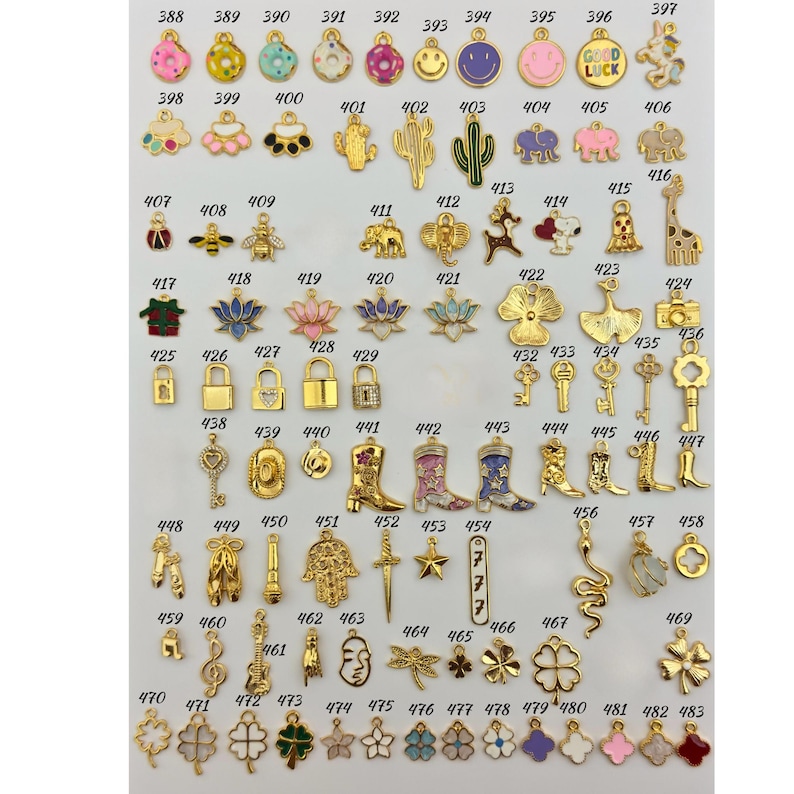 K&ouml;nnte beinhalten: Eine Sammlung goldfarbener Charms in verschiedenen Formen, darunter Smiley-Gesichter, Tiere, Schl&uuml;ssel, Stiefel und Blumen. Die Charms sind in Reihen und Spalten angeordnet und zeigen eine Vielzahl von Designs f&uuml;r die Schmuckherstellung oder das Basteln.