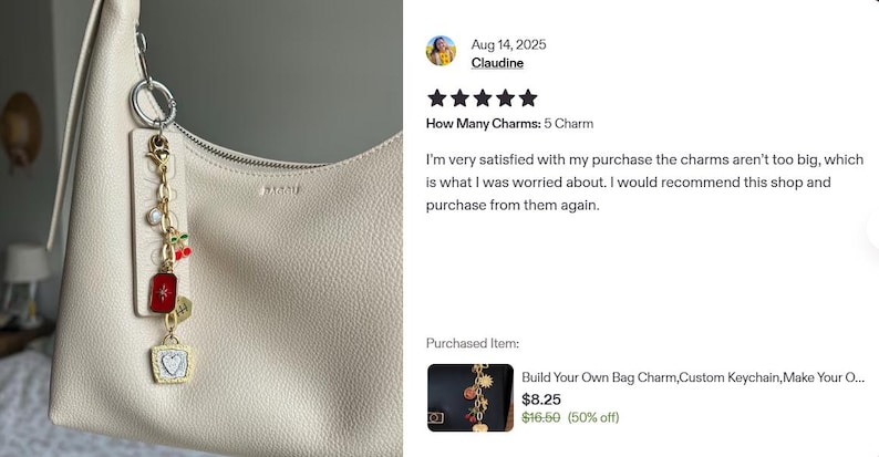 K&ouml;nnte beinhalten: Eine cremefarbene Handtasche mit einem dekorativen Anh&auml;nger. Der Anh&auml;nger hat eine goldene Kette mit verschiedenen Charms, darunter ein roter rechteckiger Charm, eine Kirsche und ein herzf&ouml;rmiger Charm. Die Tasche hat einen Rei&szlig;verschluss.