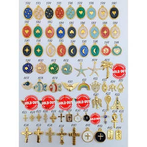 May include: Assortment of gold-tone charms with various enamel designs, including stars, hearts, moons, fish, and crosses. Some charms are marked as "Sold Out".