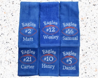 May include: Six blue towels with white embroidered text. Each towel has a football design with a number and name. The names are Matt, Wesley, Samual, Carter, Henry, and Daniel.