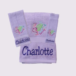 May include: A set of three lavender towels with embroidered sea turtles and the name "Charlotte" on each towel.