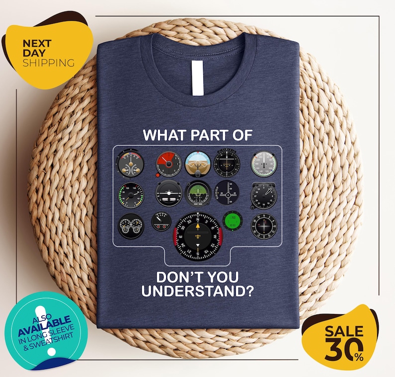 a blue t-shirt with a graphic design of various flight instruments and a question asking "Don't you understand?". The t-shirt is displayed on a woven placemat, and there are two yellow circular signs in the image.