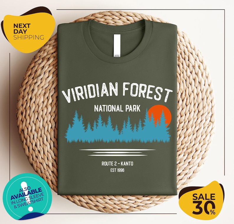 a green t-shirt with a graphic design of a forest and a route, along with text indicating it is from Viridian Forest National Park.