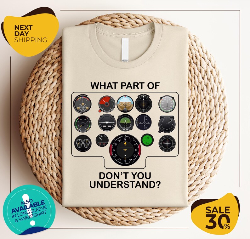 a t-shirt with a graphic design depicting various flight instruments and a question asking "What part of don't you understand?". The t-shirt is displayed on a woven placemat, and there are two yellow circular stickers with text around the image.