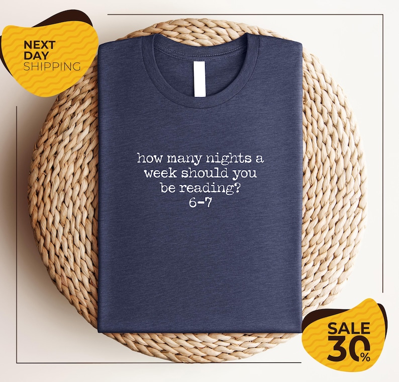 a blue t-shirt with a humorous text printed on it, placed on a woven placemat.