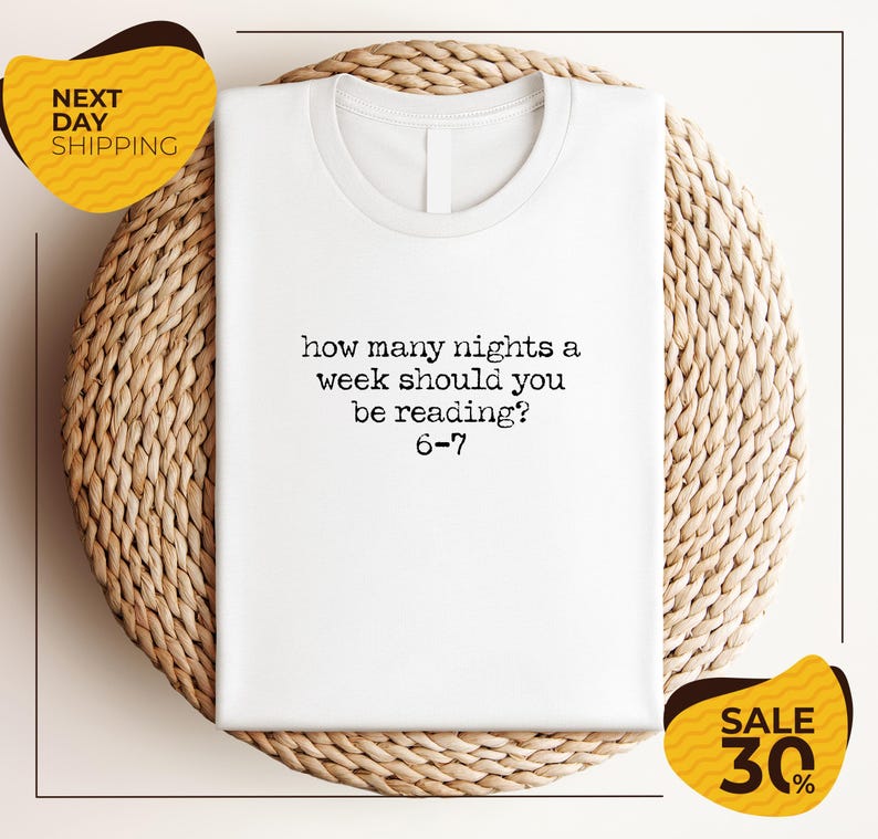A white t-shirt with a humorous text printed on it, placed on a woven placemat. The text reads "how many nights a week should you be reading 6-7". The image also includes two yellow sale signs, one for "NEXT DAY SHIPPING" and the other for "SALE 30%".
